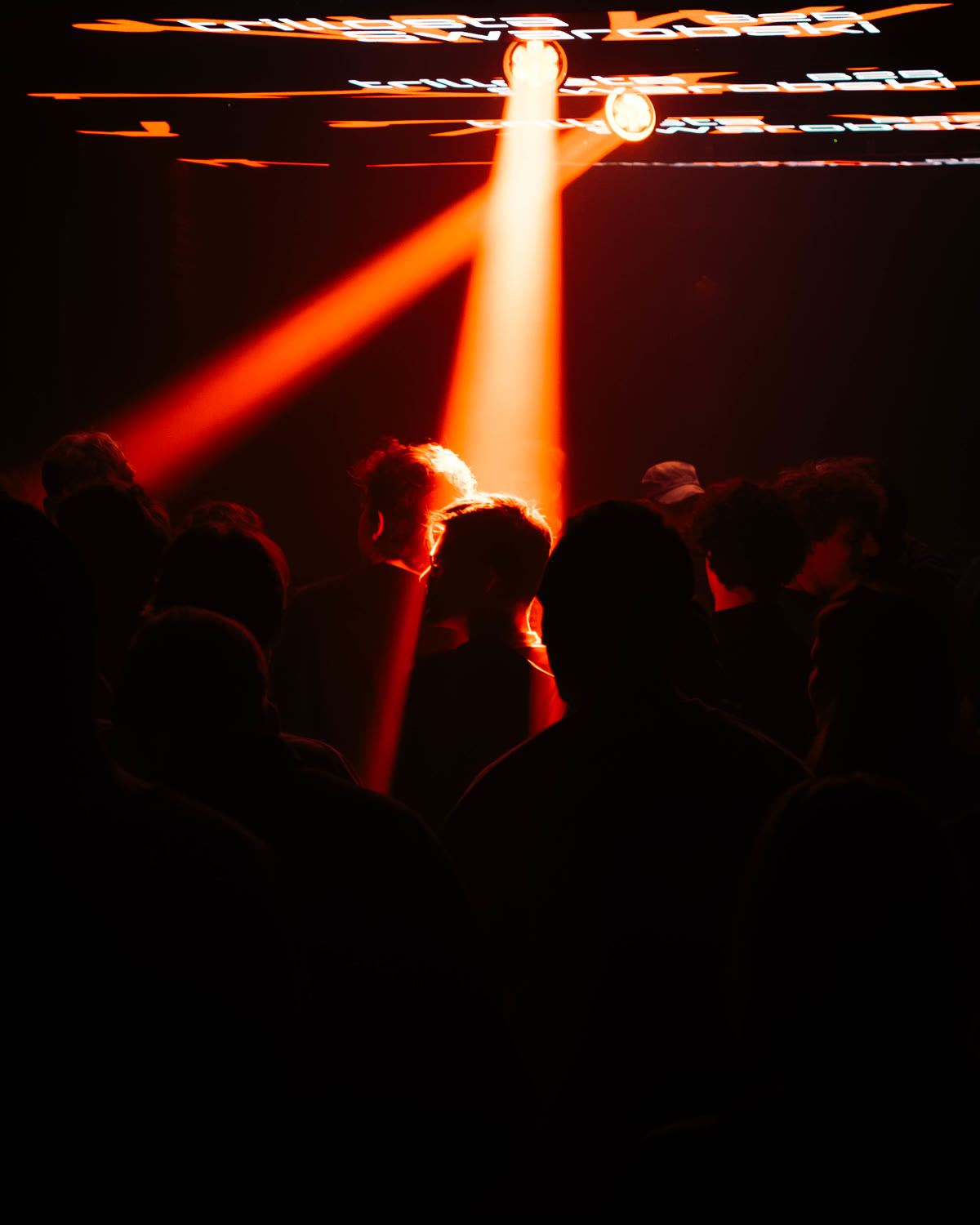Crowd facing the stage lights and screen at a KompaanEvents night